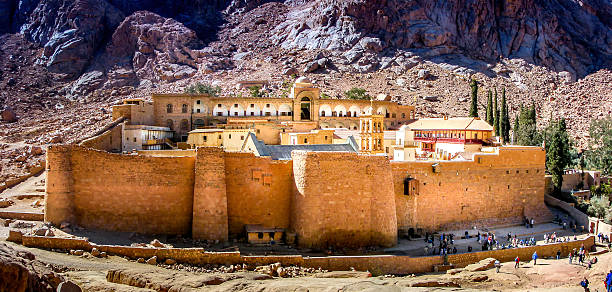 Sinai, Egypt - January 16, 2008: Saint Cathrines Monastery in Sinai, Egypt. Built in the years from 548 to 564 AD, it is one of the oldest working christian monasteries. A large group of tourists are seen near the small main entrance. During the first many centuries, there was no entrance at ground level and visitors had to be hoisted up to an entrance high up on the wall.